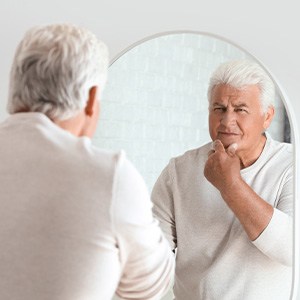 Patient looking at jawline in mirror after tooth loss