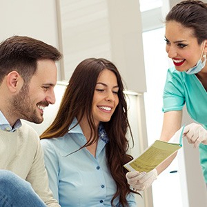 Dental assistant showing smiling couple form