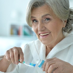 Dentures patient smiling as they prepare to brush their prosthetic