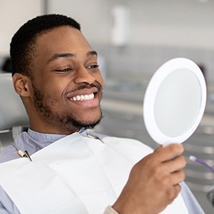 Man smiling at reflection in handheld mirror
