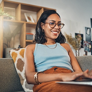 Woman smiling while working on laptop at home