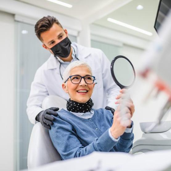 Dentist standing behind a patient while she admires her smile