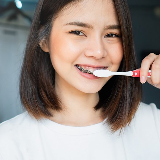 Girl brushing her teeth and cleaning her braces